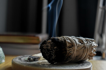 A close up image of a burning white sage smudge stick and healing crystals. Witchcraft, meditation,...