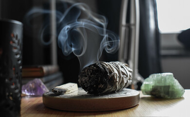 A close up image of a burning white sage smudge stick and healing crystals. Witchcraft, meditation, healing sage.