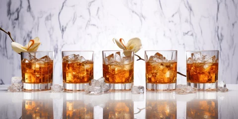 Fotobehang Row of glasses of whiskey or bourbon with ice and flowers on a white marble background. Spring advertising banner of alcoholic beverages mockup. © OleksandrZastrozhnov