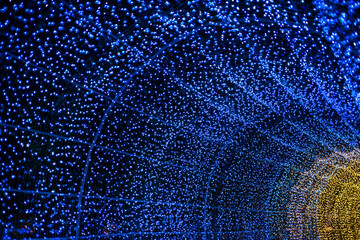 Celebration lights at Christmas New Year festival. Crowd of hanging blue light bulbs blue bokeh background. blue light bulb tunnel. 