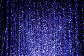 Celebration lights at Christmas New Year festival. Crowd of hanging blue light bulbs blue bokeh background. blue light bulb tunnel. 