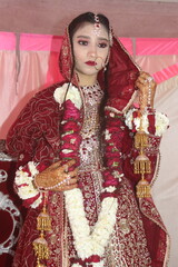 Pretty girl in traditional Indian Pakistani bridal costume with heavy makeup and jewellery, selective focus with blur in image
