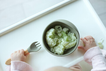 A child eats cauliflower using the self-feeding method