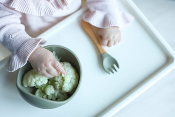 A child eats cauliflower using the self-feeding method