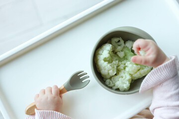 A child eats cauliflower using the self-feeding method