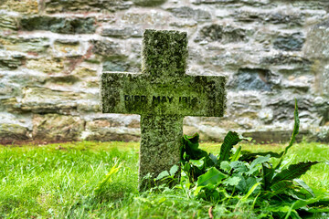 Altes Grabkreuz neben einer Kirchenmauer in Cornwall
