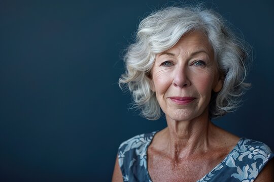A woman with short gray hair and a blue floral dress is smiling