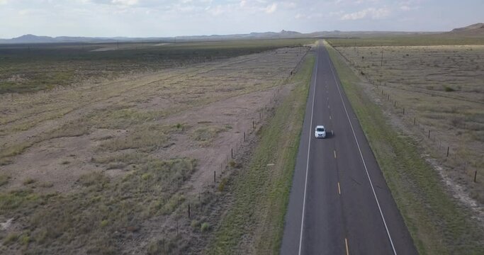 Drone &mdash; Highway in West Texas with mountains in background and car driving through