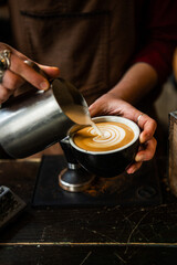 Female hands pouring milk and preparing fresh cappuccino. Coffee artist. Barista working.