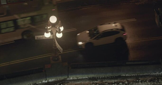 A street light illuminates street signs along a road in the historic district of Quebec City, Canada during gentle snow.