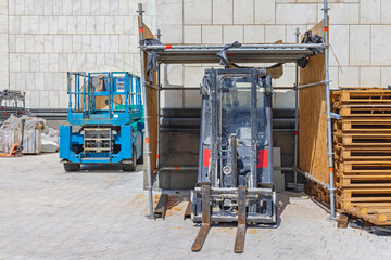 Forklift in Garage and Aerial Work Platform at Construction Site