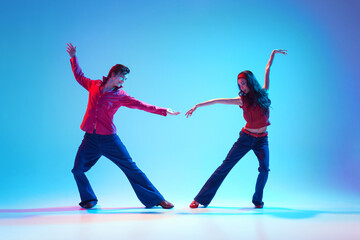 Stylish handsome young man and beautiful woman dancing rock and roll retro dance against blue...