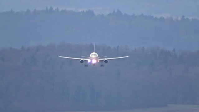 Airplane landing at airport head on generic unmarked white full landing and approach passenger jet