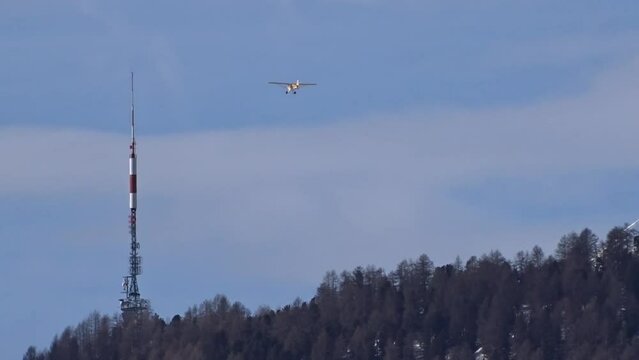 bush airplane flying far away tail view with scenic mountain background winter snow covered ice cold remote location small aircraft