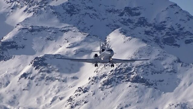 business jet flying final approach for landing at snow covered airport generic unmarked winter background landscape scenic close up