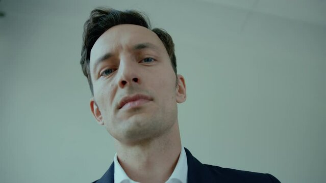 Close-up from below of face of suited young man with angry expression