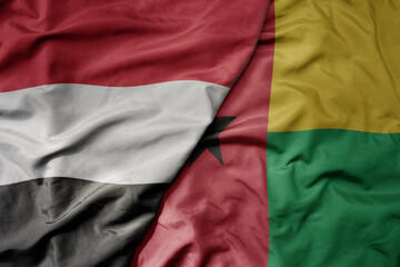 big waving national colorful flag of guinea bissau and national flag of yemen .
