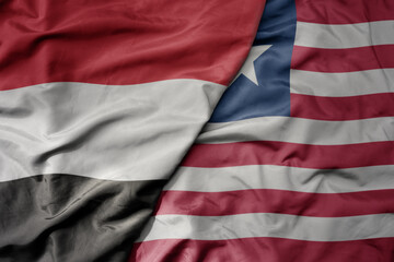 big waving national colorful flag of liberia and national flag of yemen .