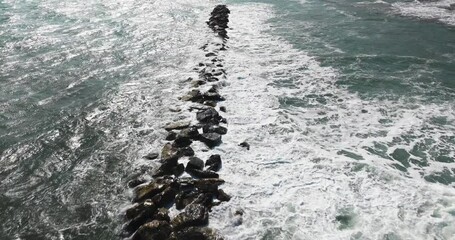 Waves crashing against an artificial breakwater. A breakwater is a permanent structure constructed at a coastal area to protect against tides, currents, waves, and storm surges.
