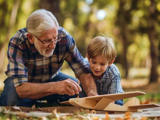 Cercles muraux Ancien avion The old man / grandfather is teaching the boy how to assemble or fix the model plane. peaceful and heartwarming scene in the backyard/outdoor park