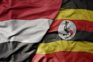 big waving national colorful flag of uganda and national flag of yemen .