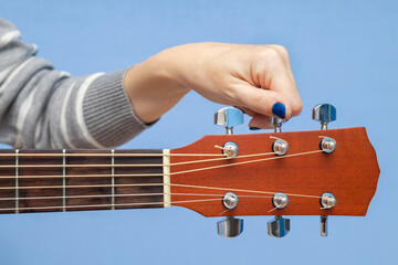 Woman tuning an acoustic guitar, shot close-up.
