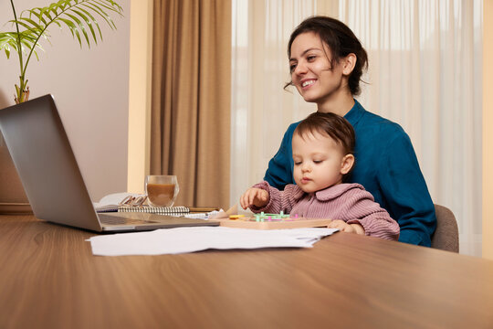 happy beautiful businesswoman working on laptop with her little child girl at home
