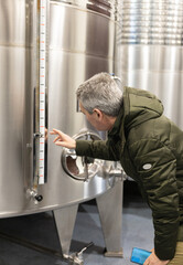 Fototapeta na wymiar winemaker checking wine tank levels in winery, copy space.