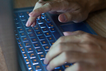 Close up image of hands typing on laptop computer keyboard and surfing the internet at home....
