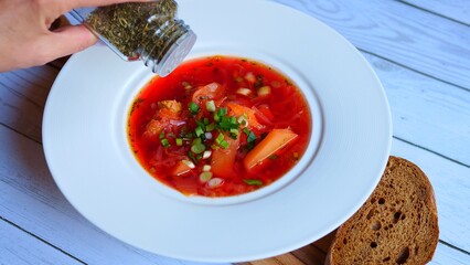 Immerse in authenticity of Ukrainian cuisine with spices gently falling into steaming bowl of traditional soup. Perfect for culinary enthusiasts seeking vibrant visuals Capture essence of soups warmth