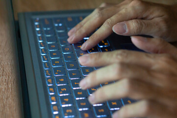 Close up image of hands typing on laptop computer keyboard and surfing the internet at home....