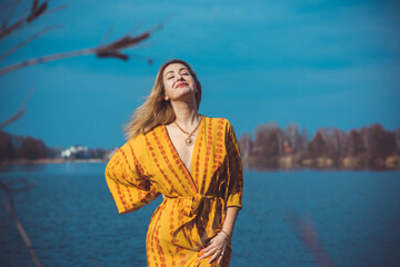 Fototapeta na wymiar Woman in yellow cotton robe at nature. Boho style, relaxed freedom feeling concept