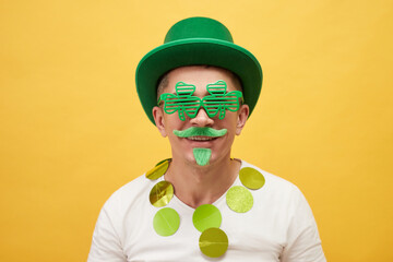 Saint Patrick's Day party. Smiling cheerful man wearing green leprechaun hat and shamrock glasses...