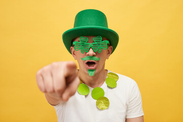 Shocked frighten scared man wearing green leprechaun hat and shamrock glasses posing isolated over...