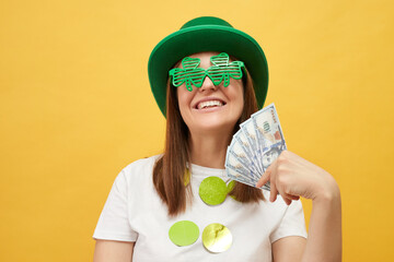Satisfied joyful woman wearing green leprechaun hat and shamrock glasses posing isolated over...