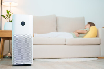 Air Purifier with woman relax and sleep on sofa. Purification system for filter and cleaning dust...