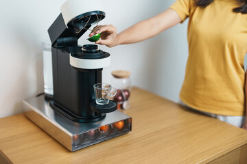 hand making Espresso Coffee by Coffee Maker Machine with Capsule of roasted coffee bean on wood...