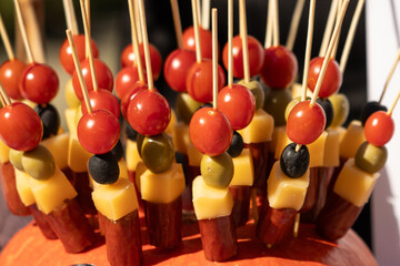 appetizer of tomato cheese and olives on a wooden stick.