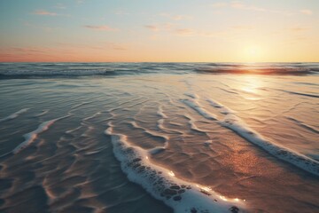 a beach with sand patterns, with the sun setting in the distance and its reflection on the water's surface, the colors of the sky and the sea blending together in a mesmerizing way