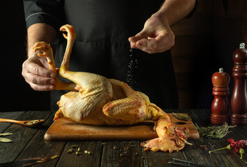 The chef is preparing a rooster on the kitchen table in a public house. Concept of cooking...