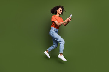 Fototapeta na wymiar Full length photo of excited cute woman wear t-shirt jumping chatting instagram twitter telegram facebook isolated green color background