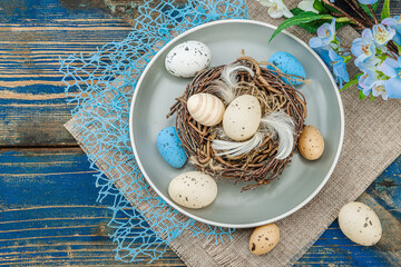Easter table setting with eggs, bird's nest and blooming branch. Traditional festive symbols