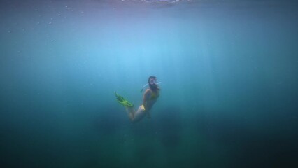 Young Caucasian woman swims snorkeling underwater. A mask of fins and a snorkel helps you swim underwater. Slow motion