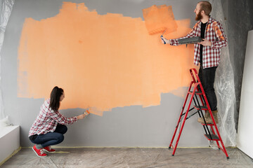 Happy young couple decoration room in new home painting wall together. Renovation diy concept.
