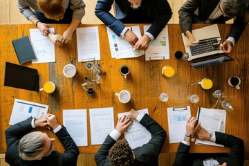A diverse group of individuals sitting together around a large wooden table engaged in a lively discussion, Overhead view of a professional meeting with documents and coffee cups, AI Generated - obrazy, fototapety, plakaty
