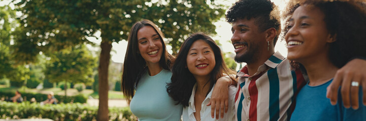 Happy multiethnic young people walk embracing on summer day outdoors, Panorama. Group of friends...