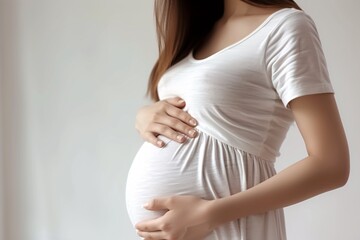 a pregnant woman in a white dress holding her belly - obrazy, fototapety, plakaty