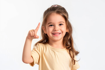Portrait of a little cute girl in a peach T-shirt with curly hair points her finger up on a white background. Copy space