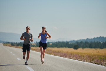 Energized by the beauty of nature, a couple powers through their morning run, their bodies and...