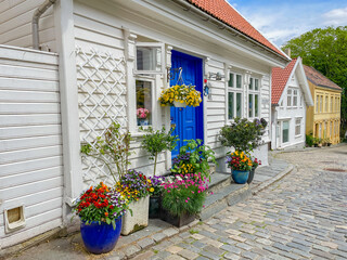 Beautiful wooden house with many flowers in front of it and a blue wooden door, Stavanger, Norway - 757207610